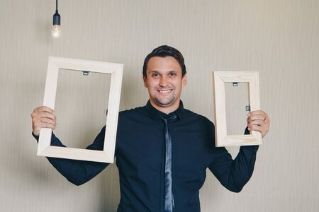 beautiful man smiling near the empty frame. Copy space. The concept of empty space for advertising, models for demonstration of textsの写真素材