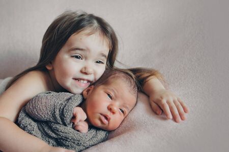 the concept of a healthy lifestyle, the protection of children, shopping - a child with a newborn baby playing together. Happy kids: girls on white backgroundの写真素材