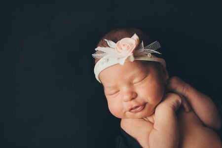 portrait of a sleeping newborn baby in a headband with flower. Health concept: IVF, baby accessoriesの写真素材