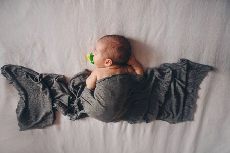 the concept of healthy lifestyle, IVF - a newborn baby sleeps under a blanket with a pacifier in his mouth.の写真素材