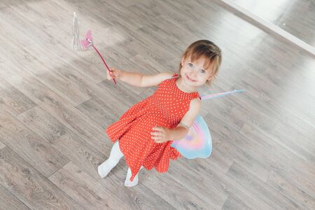 A little girl with colorful wings. A child in a fairy costume. Christmas concept, mystical creatures, Halloween, carnival, costume partyの写真素材