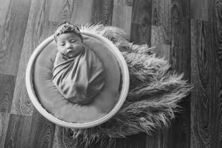newborn baby wrapped in a blanket sleeping in a basket. concept of childhood, healthcare, IVF. Black...