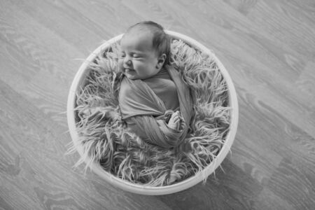 newborn baby wrapped in a blanket sleeping in a basket. concept of childhood, healthcare, IVF. Black and white photoの写真素材