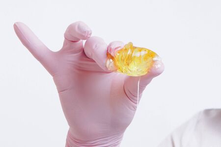 wax for depilation close-up. The girl demonstrates a cosmetic product. The doctor's gloved hand. Sugaring: hair removal with liquid sugar. This is a less painful hair removal with wax replacementの写真素材