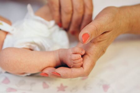 Newborn Baby's feet.Mother holding newborn baby legs,legs massageの写真素材