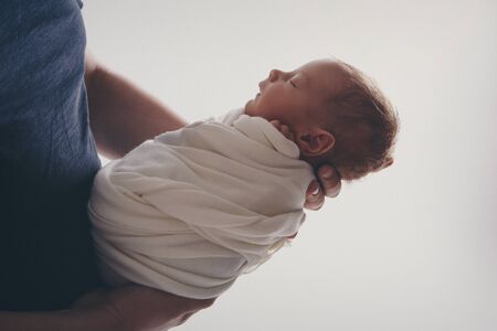 Newborn baby lying on hands of parents. Imitation of baby in womb. beautiful little girl sleeping on her back. manifestation of love. Health care concept, parenthood, children's Day, medicine, IVFの写真素材