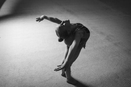 A girl in a tracksuit doing exercises with ball on a white background.の写真素材