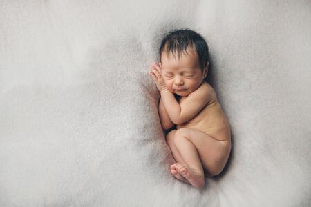 naked Newborn baby lying. Imitation of baby in womb. beautiful little girl sleeping on her back. manifestation of love. Health care concept, parenthood, children's Day, medicine, IVFの写真素材