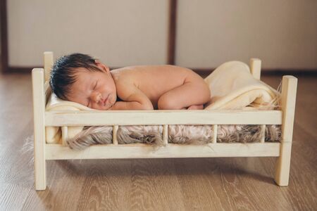 naked baby lying in a wooden bed. portrait of little child. the concept of childhood, health, IVF, children's furniture, interior, wood productsの写真素材