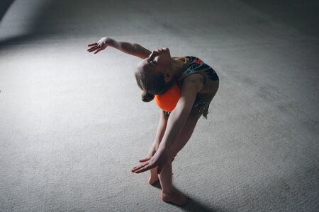 A girl in a tracksuit doing exercises with ball on a white background. Healthy lifestyle conceptの写真素材