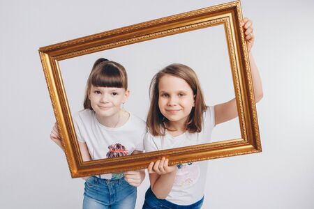 the concept of a healthy lifestyle , child protection, shopping - these are teenagers playing together. Happy children: sisters on a white background. Live picture - the girls look out of the frameの写真素材