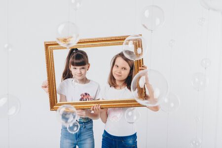 the concept of a healthy lifestyle , child protection, shopping - these are teenagers playing together. Happy children: sisters on a white background. Live picture - the girls look out of the frameの写真素材