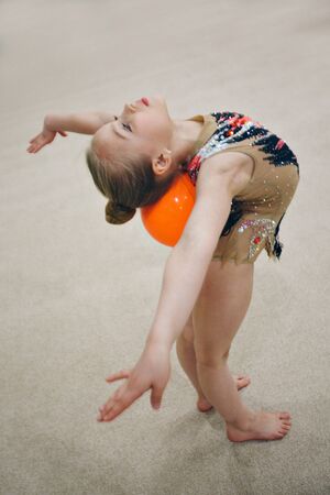 A girl in a tracksuit doing exercises with ball on a white background. Healthy lifestyle concept, sports uniforms,   gym, specialized clothing, uniformsの写真素材