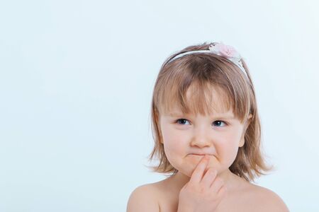 a little girl grimaces against a white background. The child is up to something. Concept of emotions...
