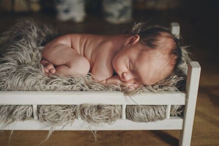 naked baby lying in a wooden bed. portrait of little child. the concept of childhood, health, IVF,...