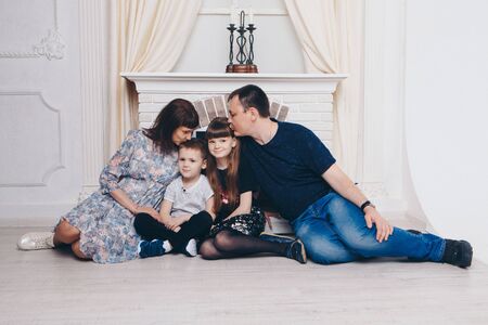 Warming and relaxing near fireplace. Mother, father and daughte, son hugging. Concept of family ,...