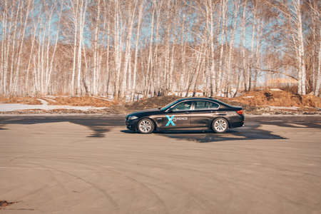 advertising BMW, Moscow, 1.11.2018: demonstration of the black car model, cars in the test track, dust from under the wheels, tracks on the road, race, driving training in a driving schoolのeditorial素材