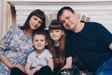 Warming and relaxing near fireplace. Mother, father and daughte, son hugging. Concept of family , motherhood, interior, home, childhood, mother's day, children's dayの写真素材
