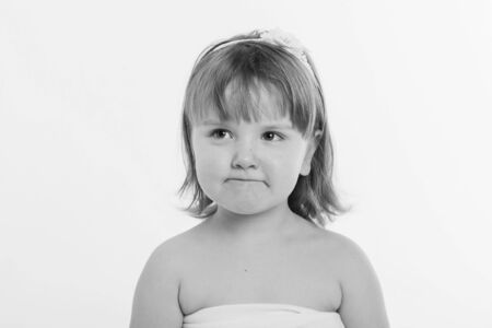 a little girl grimaces against a white background. The child is up to something. Concept of emotions...