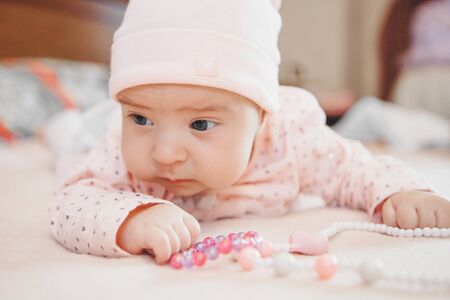 child plays with colored beads. girl becomes little lady. Concept of fine motor skills development, educational games, childhood, children's day, kindergarten. Ads for costume jewelry and fashion.の写真素材