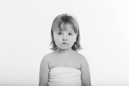 a little girl grimaces against a white background. The child is up to something. Concept of emotions , facial expressions, childhood, sincerityの写真素材