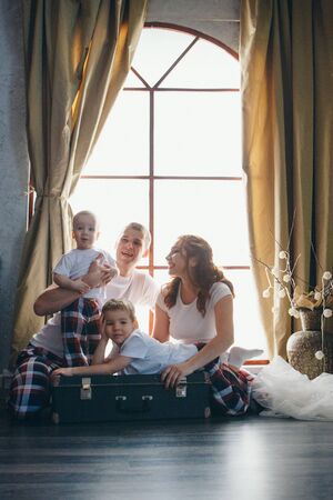 a loving couple with children hugs on the floor near a decorative vase. A man and a woman look into each other's eyes. Valentine's day. February 14, children's day, family dayの写真素材