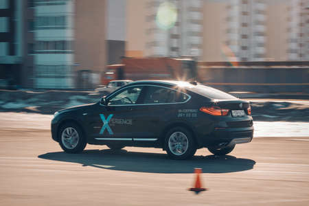 BMW advertising, Moscow, 1.11.2018: demonstration of a model of a black car, cars on a test track, dust from under the wheels, tracks on the road, racing, driving training in a driving school, delivery around the city, taxiのeditorial素材