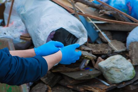 a man wears rubber gloves for garbage collection. a lot of garbage in the container. garbage...