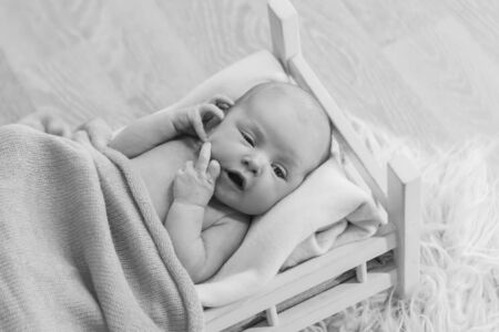 baby lying in a wooden bed under a blanket. portrait of little child. the concept of childhood, health, IVF, children's furniture, interior, wood productsの写真素材