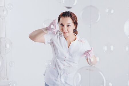 The doctor in rubber gloves. A girl wears a protective gear during an epidemic. Ads for antiseptics and medical equipment on a white background. Free medical care. Volunteers in the hospitalの写真素材