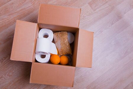 essential products for self-isolation in a box: cereals. toilet paper, fruit, canned food. home delivery. Assistance to populationの写真素材