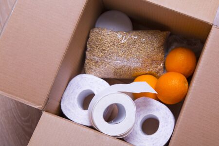 essential products for self-isolation in a box: cereals. toilet paper, fruit, canned food. home...