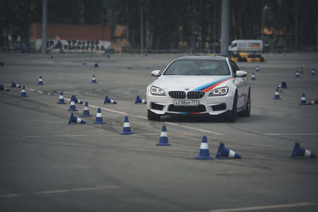 advertising BMW, Moscow, 1.11.2018: demonstration of the white car model, cars in the test track, dust from under the wheels, tracks on the road, race, driving training in a driving school, delivery around the city, taxiのeditorial素材