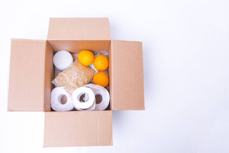 essential products for self-isolation in a box: cereals. toilet paper, fruit, canned food. home delivery. Assistance to populationの写真素材