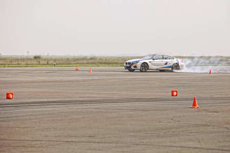 advertising BMW, Moscow, 1.11.2018: demonstration of the white car model, cars in the test track, dust from under the wheels, tracks on the road, race, driving training in a driving school, delivery around the city, taxiのeditorial素材