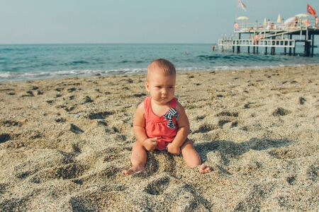 a small child plays in the sand. girl sitting on the beachの写真素材