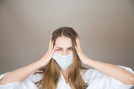 Portrait of a girl who covered her face with a mask. Frightened eyes of the patient.の写真素材