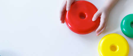 child plays with detail from pyramid. round multicolored details from toy on white background. fine...