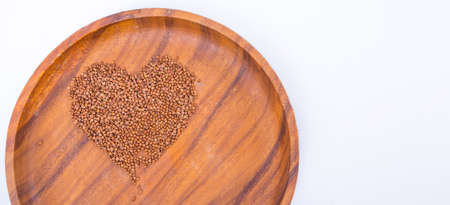 Theme of diet and weight loss on a white background. buckwheat in a wooden plate is laid out in the...