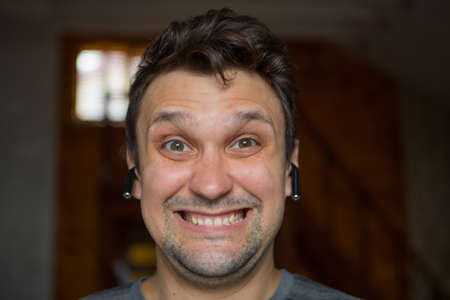 the happy guy inserts a wireless headset into his ear. Man and modern technologies. listen to music....