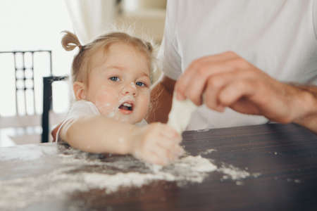 the baby makes cakes. the children were covered in flour. dinner at the bakery. feast in the kitchenの写真素材