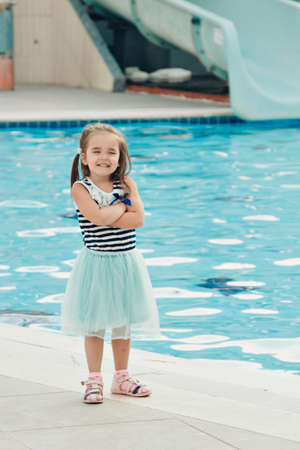 A little girl walks by the pool. Holidays in hot countries. the territory of the hotel