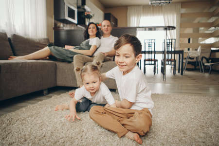 A family with two children is sitting on the sofa. Weekend at home. Spending time together