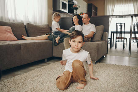 A family with two children is sitting on the sofa. Weekend at home. Spending time together