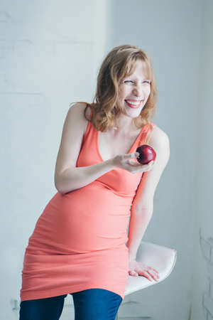 portrait of a pregnant woman with an Apple in her hand. Calm expectant mother. Lunch break, snack