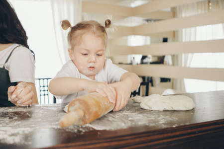 the baby makes cakes. the children were covered in flour. dinner at the bakery. feast in the kitchenの写真素材