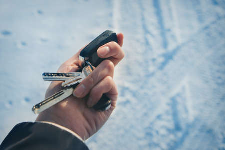 keychain with car keys in hand on the background of snow. trying to start a car in winterの写真素材