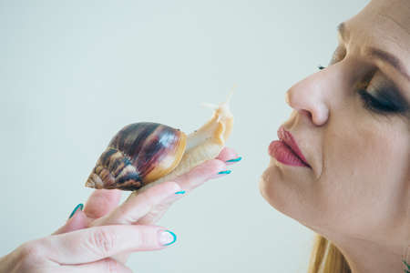 model holds snail on hand. ads for cosmetics, anti-gravity creams, lip treatments, face treatments, botax, rejuvenation, healthy nutrition, wrinkles and anti-wrinkles. Concept of French cuisineの写真素材