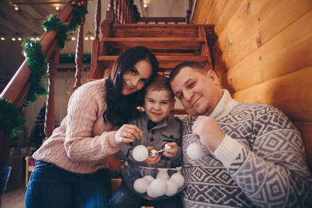 the family is sorting out Christmas toys. white snowballs for parents and children. preparation for holidays: new yearの写真素材