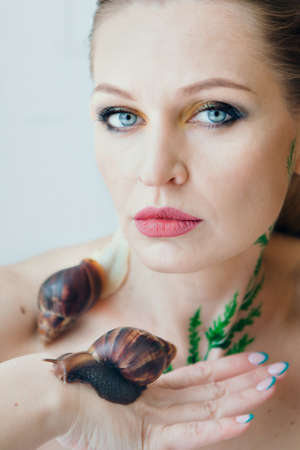 model holds snail on hand. ads for cosmetics, anti-gravity creams, lip treatments, face treatments,...